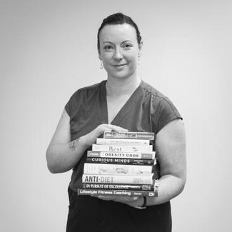 A smiling woman holding a stack of textbooks
