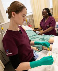 2 students preparing medical supplies for mannequin in health lab